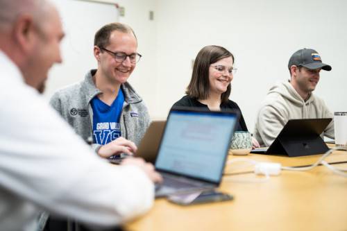 Grand Valley students sitting around a table with their laptops open